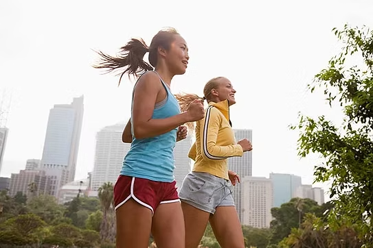 Active mother and daughter jogging together outdoors, representing comprehensive women's health and wellness services including preventive care and lifestyle counseling